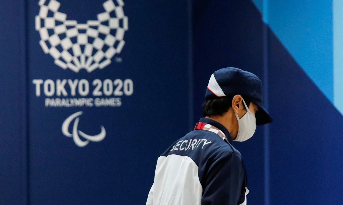 Segurança usando máscara de proteção passa em frente a logo dos Jogos Parlímpicos Tóquio 2020 em Tóquio - Paralimpíada - l
