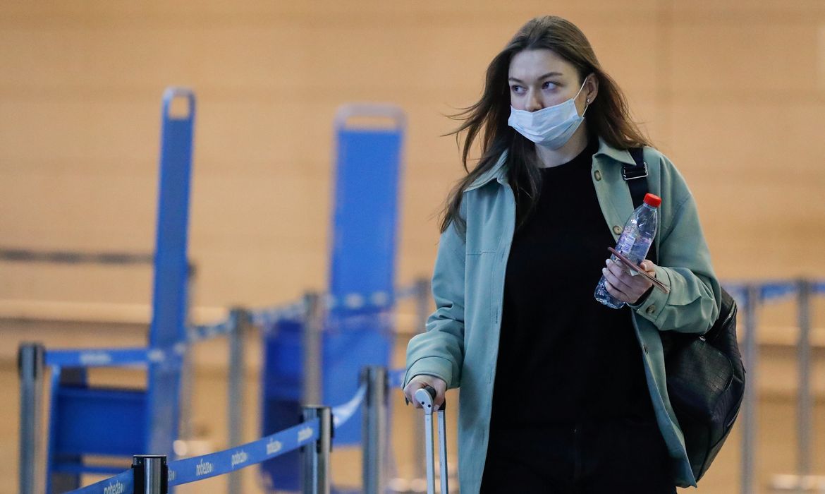 Mulher usando máscara de proteção caminha na área de embarque do aeroporto de Vnukovo, em Moscou