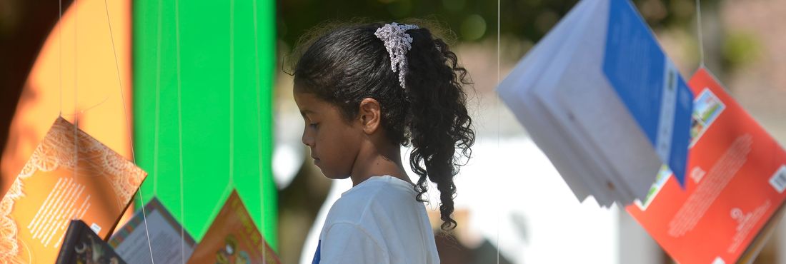 Livros infantis pendurados em árvores atraem crianças na Praça da Matriz durante a 12ª Festa Literária Internacional de Paraty