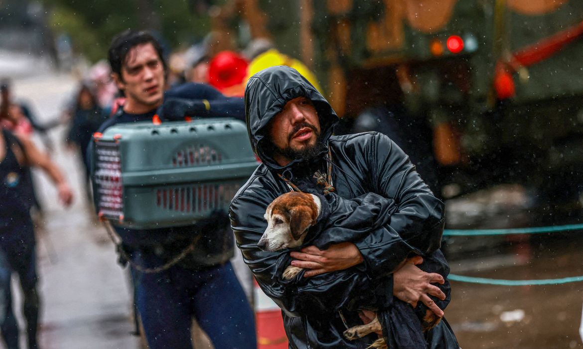 A volunteer carries a dog that has been rescued from a flooded area in Porto Alegre, Rio Grande do Sul state, Brazil May 10, 2024. REUTERS/Diego Vara