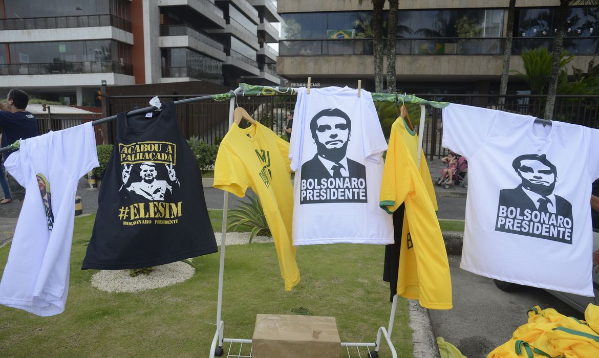 Diversos artigos com referências a Jair Bolsonaro são vendidos em frente à sua residência, na Barra da Tijuca, zona oeste da capital fluminense.