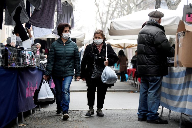 Women in face masks walk at the local market in Milan