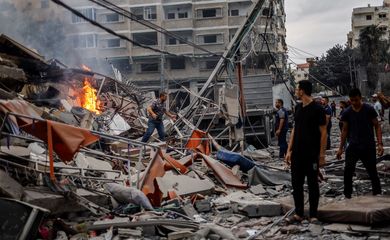 Palestinos caminham em meio a destroços de prédios destruídos por Israel em Gaza