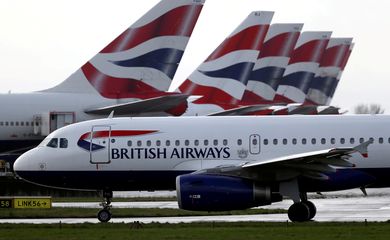 FILE PHOTO: A British Airways plane taxis past tail fins of parked aircraft at Heathrow Airport in London