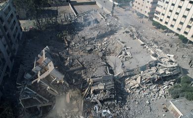 Palestinos se reúnem em torno de prédios residenciais destruídos em ataques israelenses na cidade de Zahra, em meio ao conflito em curso entre Israel e o grupo islâmico palestino Hamas, ao sul da Cidade de Gaza. 19 de outubro de 2023. REUTERS/Shadi Tabatibi
