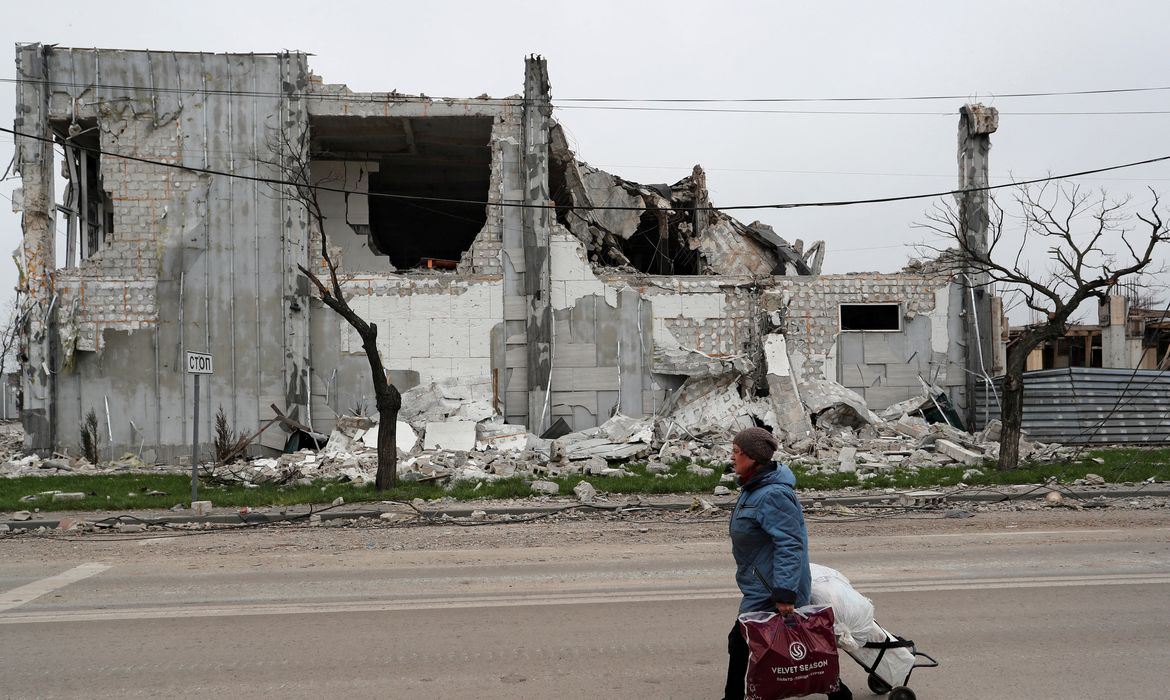 FILE PHOTO: A local resident walks past a destroyed building in Mariupol