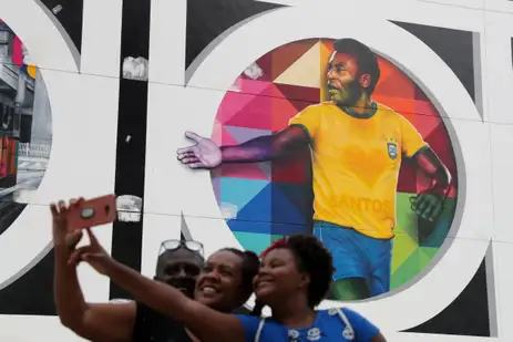 Fãs tiram foto em frente a mural de Pelé em Santos