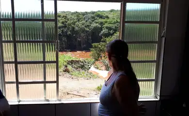 Sandra Maria observa o local tomado pela lama da janela de sua casa em Brumadinho 