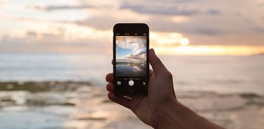 Pessoa tira foto do oceano com celular