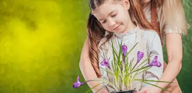 Mãe segura vaso de planta com filha envolvendo-a em abraço