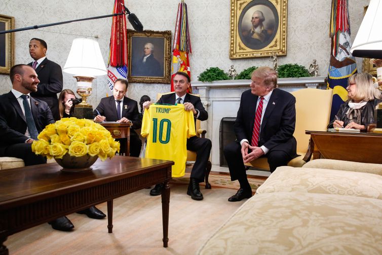 O presidente do Brasil, Jair Bolsonaro, dá uma camiseta da Seleção Brasileira de futebol para o presidente dos EUA, Donald Trump, durante reunião no Salão Oval da Casa Branca, em Washington (EUA). 