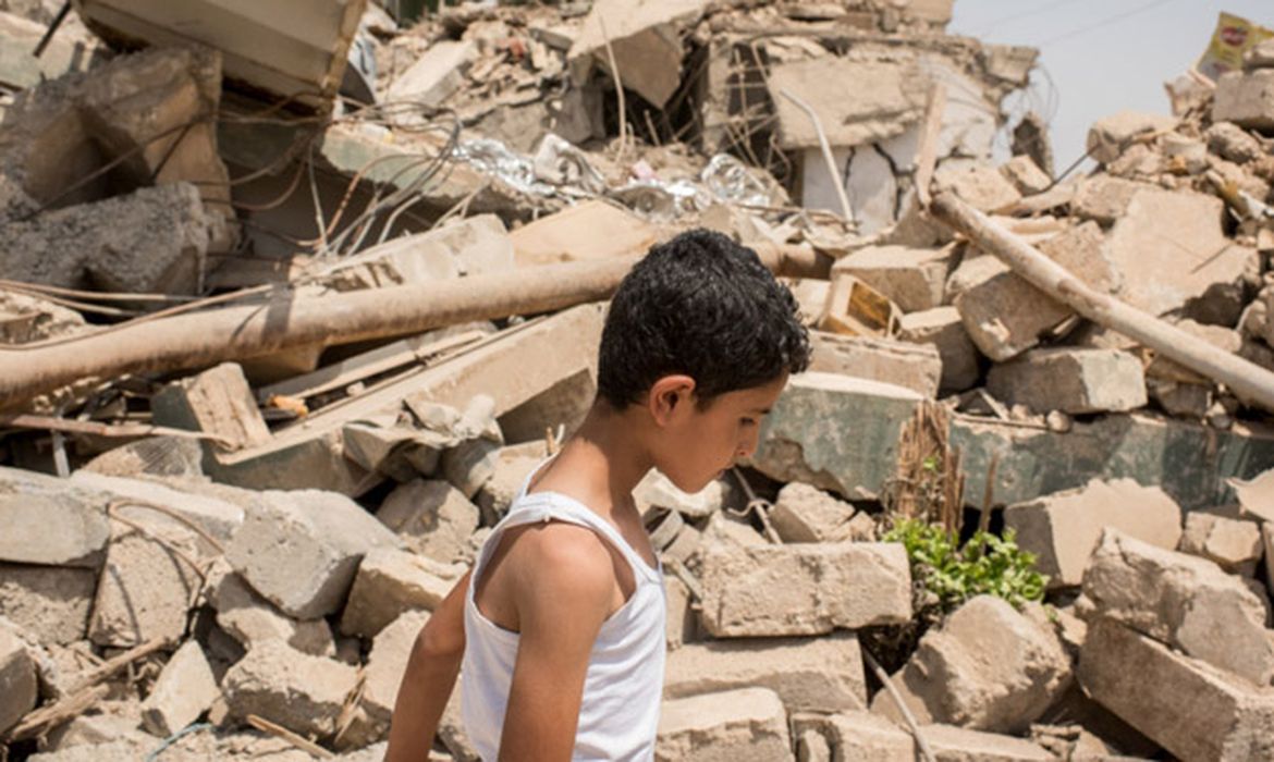 Menino passa em frente a casas destruídas no bairro de Al-Resala, na região oeste de Mossul, no Iraque