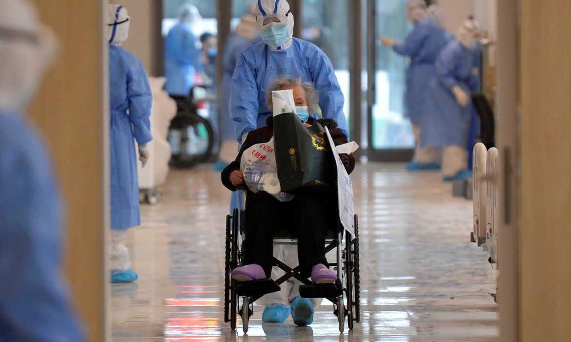 Medical worker in protective suit moves a novel coronavirus patient in a wheelchair at a hospital in Wuhan