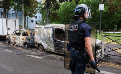 Um policial francês faz guarda ao lado de veículos queimados durante uma noite de confrontos entre manifestantes e policiais, após a morte de um adolescente de 17 anos morto por um policial francês durante uma parada de trânsito, em Nanterre, subúrbio de Paris, França, em 1º de julho de 2023. REUTERS/Yves Herman