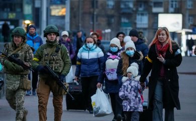 Militares escoltam pessoas com crianças para trem de saída de Kiev