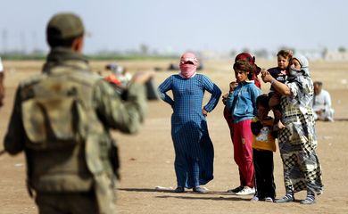 Refugiados sírios aguardam na fronteira com a Turquia para fugir dos ataques do Estado Islâmico (EPA/Sedat Suna/Agência Lusa)
