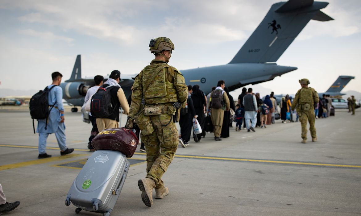 Australian citizens and visa holders prepare to board the Royal Australian Air Force C-17A Globemaster III aircraft, as Australian Army infantry personnel provide security and assist with cargo, at Hamid Karzai International Airport in Kabul