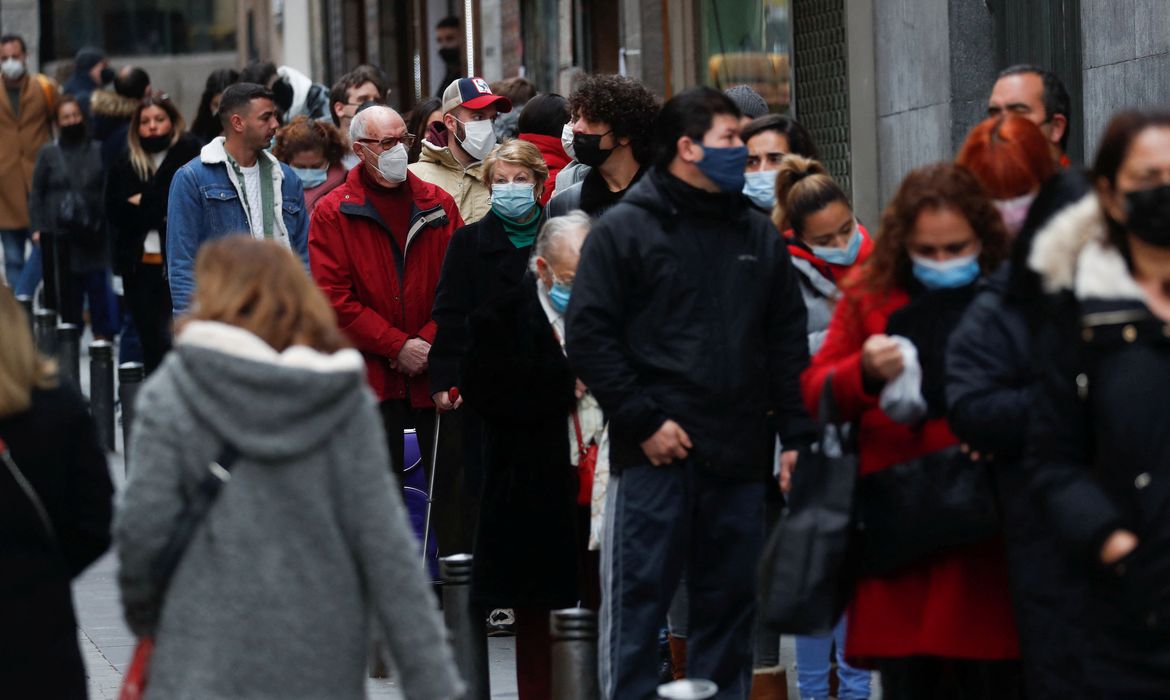 People wearing face masks queue to buy Christmas lottery tickets, in Madrid