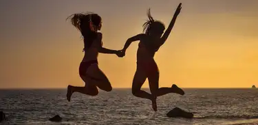 Duas mulheres na praia pulando e celebrando o verão