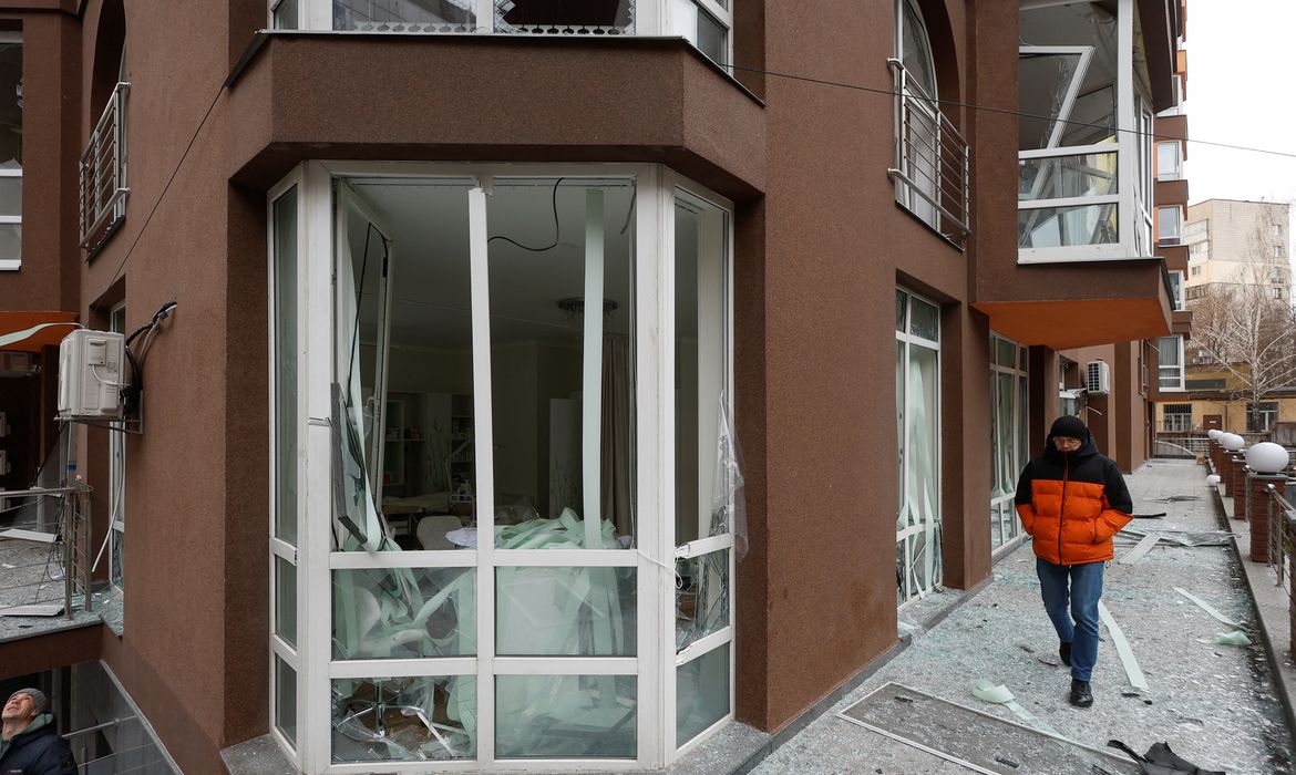 Homem anda em área de prédio residencial abalado por um ataque de drones russos a Kiev