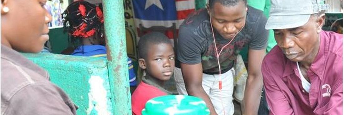 Mulher higieniza mãos de homem na Libéria; população deve continuar atenta ao ebola