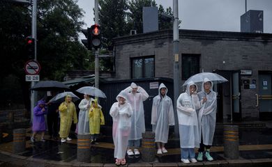 Pedestres usam capa de chuva em região turística de Pequim