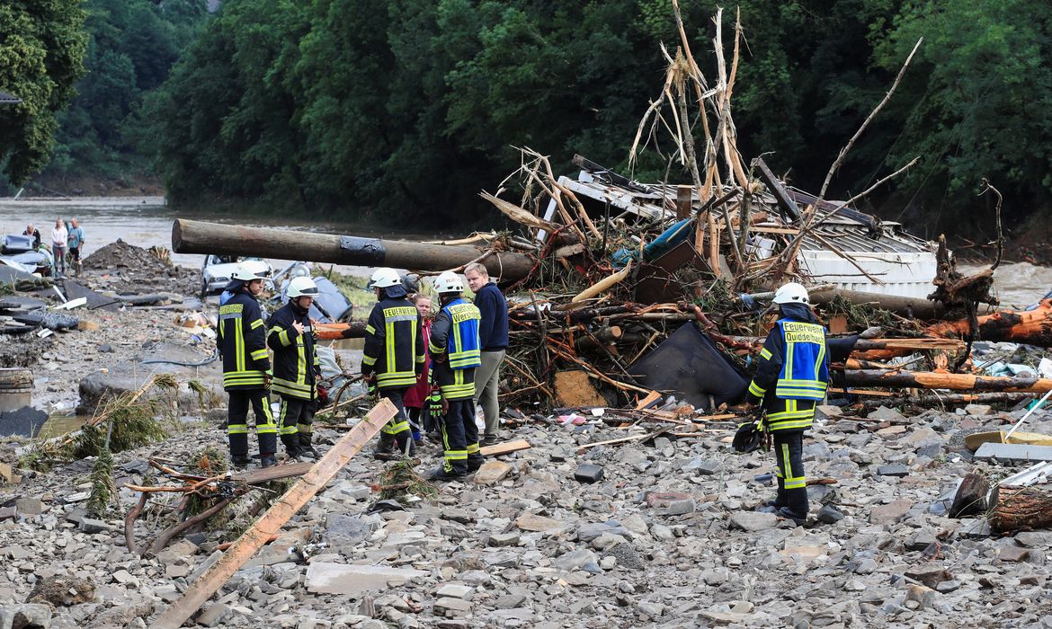 Bombeiros conversam com pessoas perto de escombros deixados pelas enchentes em Schuld, na Alemanha