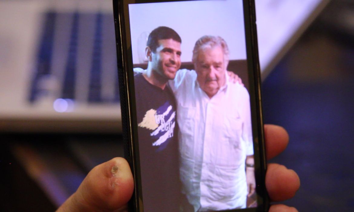 Ex-preso de Guantánamo mostra foto da visita que recebeu do ex-presidente Pepe Mujica (Reprodução TV Brasil/Monica Yanakiew)