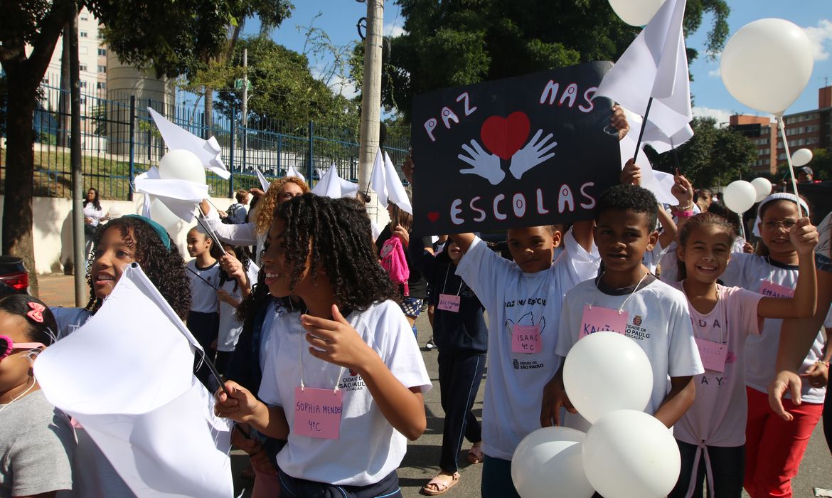 Caminhada estudantil por paz e segurança nas escolas Estudantes participam de caminhada pela paz com cartazes e balões brancos, defendendo segurança e o fim da violência nas escolas.