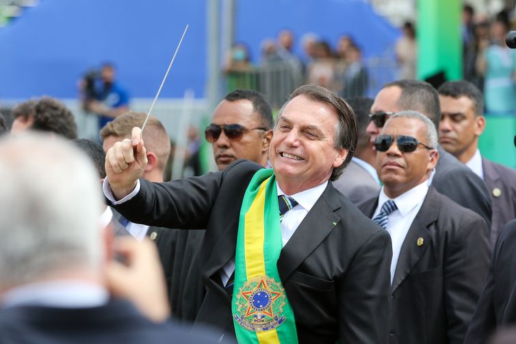O presidente Jair Bolsonaro,quebra o protocolo  desce do palanque, pega uma batuta e faz gestos de maestro ao se aproximar a pé, das arquibancadas onde fica o público na Esplanada dos Ministérios