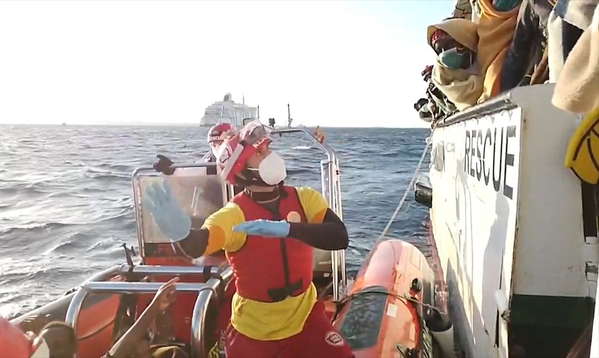 A still image taken from a video shows a rescuer of Spanish NGO Open Arms giving instructions to migrants on board rescue ship Open Arms before the transfer to quarantine ship 'Adriatico' anchored off Trapani