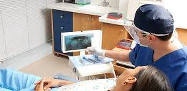 Dentista examina radiografia ao lado de paciente