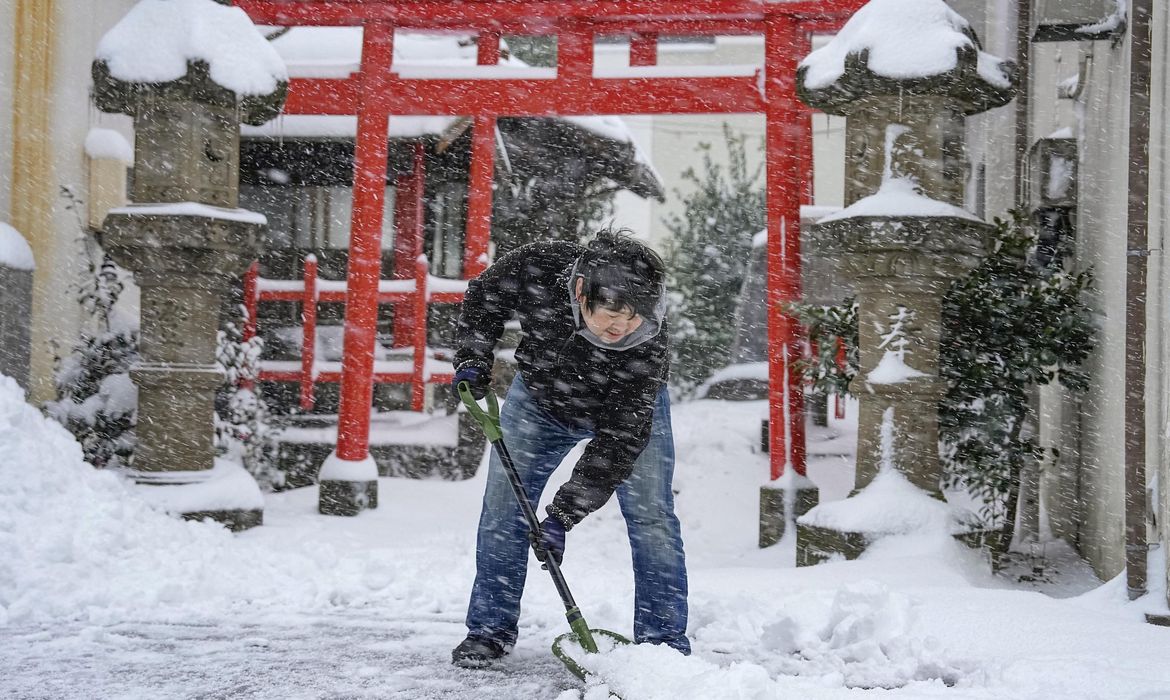 Homem limpa a neve na frente de templo em Tottori, Japão