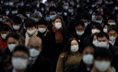 Commuters wearing protective face masks amid the COVID-19 pandemic make their way at a train station in Tokyo