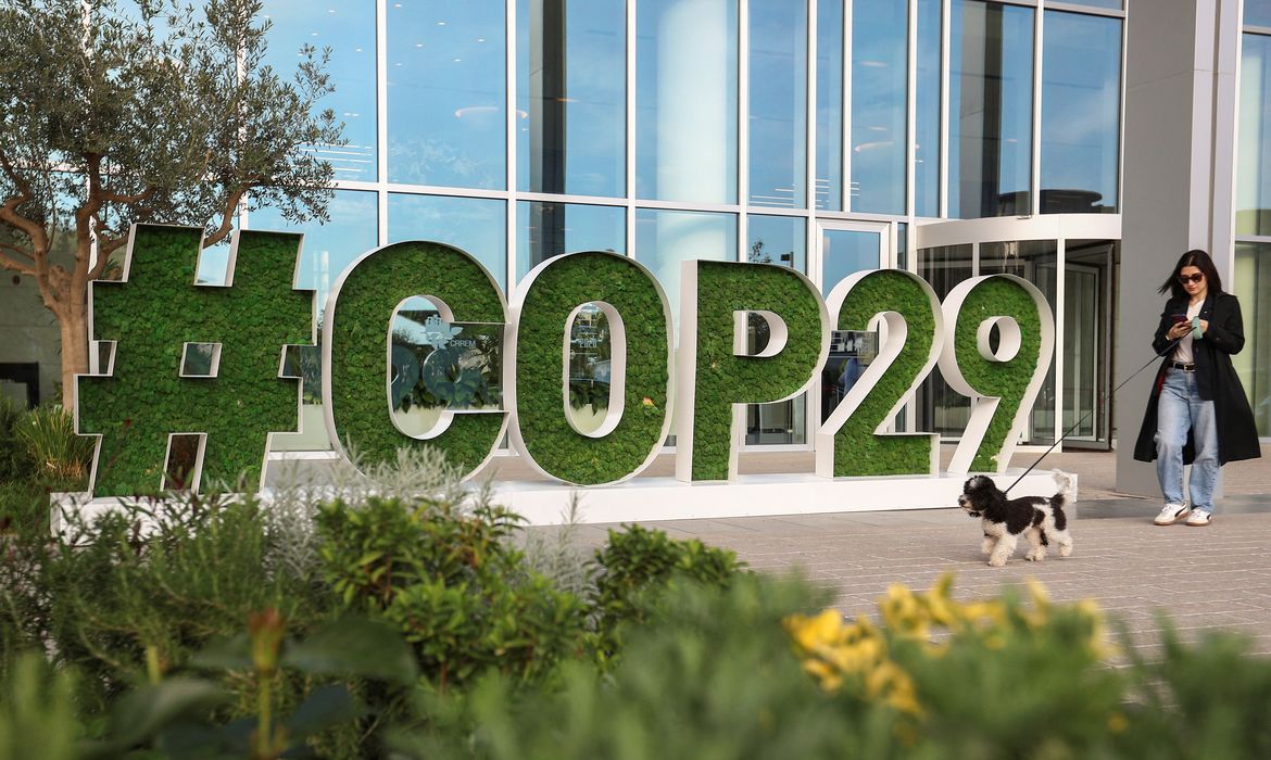 A woman walks past a sign of the COP29 United Nations Climate Change Conference, in Baku, Azerbaijan October 31, 2024. Reuters/Aziz Karimov/Proibida reprodução