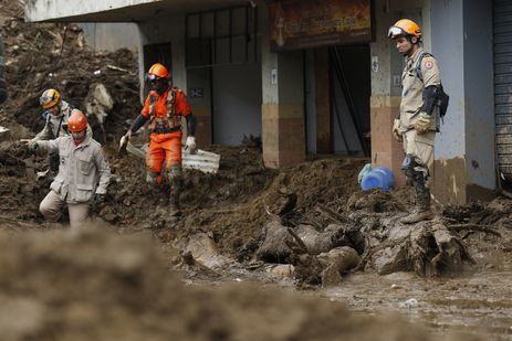 Bombeiros se equilibram sobre a lama acumulada na Rua Teresa, em trabalho de busca nos deslizamentos de terra das chuvas em Petrpolis.