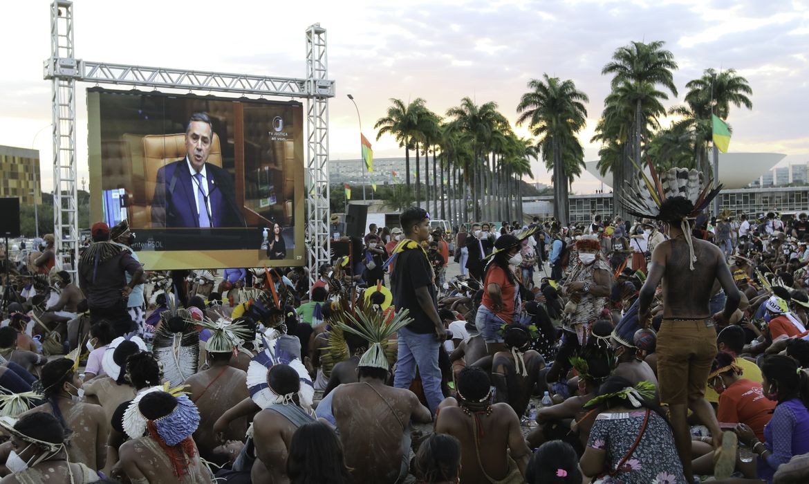 Indígenas acompanham  sessão em um telão montado em frente ao Supremo Tribunal Federal (STF), na Praça dos Três Poderes