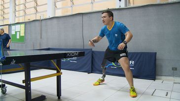 Em uma extremidade da mesa de tênis, Paulo Salmin com uma raquete na mão direita