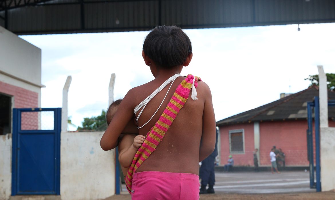 Boa Vista (RR), 15/02/2023, Criança carrega bebê em frente ao Hospital de Campanha Yanomami montado na Casa de Saúde Indígena - Casai.