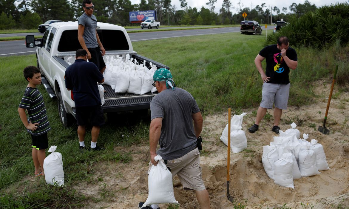 Homens carregam sacos de areia antes da chegada do furacão Dorian em Titusville