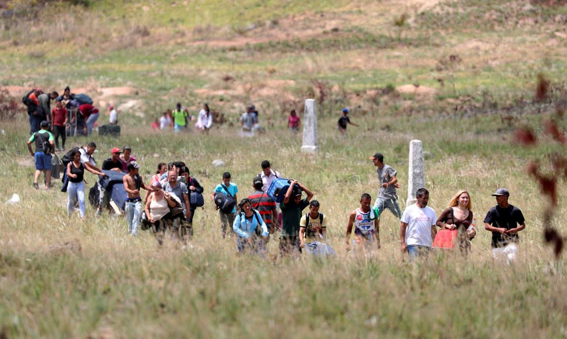 Pessoas caminham para tentar atravessar a fronteira entre a Venezuela e o Brasil em Pacaraima.