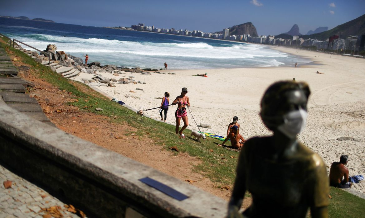 Uma estátua é vista com uma máscara facial enquanto as pessoas aproveitam o clima na praia do Leme, após o surto da doença por coronavírus (COVID-19), no Rio de Janeiro, Brasil, em 29 de abril de 2020. Foto tirada em 29 de abril de 2020.