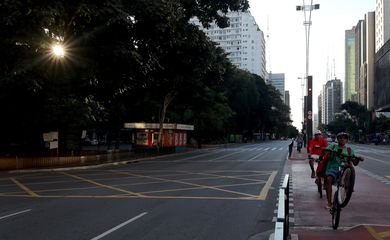 A Avenida Paulista é vista vazia enquanto os entregadores andam de bicicleta no primeiro dia de um bloqueio imposto pelo governo estadual por causa do surto de doença por coronavírus (COVID-19)