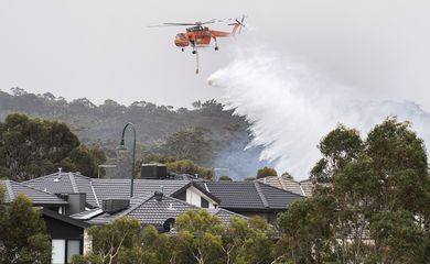 A Sikorsky S-64 Skycrane helicopter drops water on a bushfire in scrub behind houses in Bundoora, Melbourne, Australia,December 30, 2019. AAP Image/Ellen Smith via REUTERS  ATTENTION EDITORS - THIS IMAGE WAS PROVIDED BY A THIRD PARTY. NO RESALES