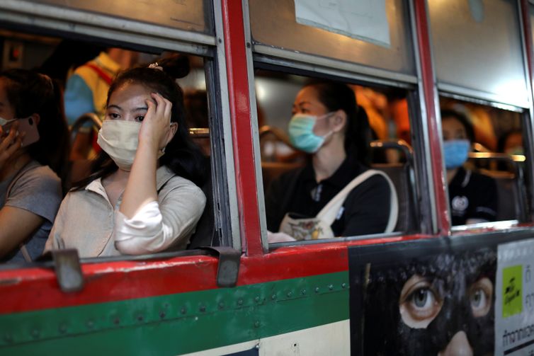 Mulheres viajam em um ônibus público usando máscaras protetoras devido ao surto de coronavírus, em Bangkok, Tailândia.