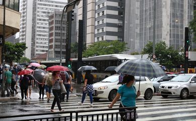 Pessoas se protegem da chuva na Avenida Paulista.