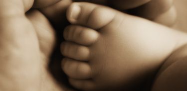 Mão segura pé de bebê