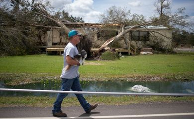 Um residente local Clint Pippen segura seu cachorro Barkley enquanto ele passa por linhas de transmissão para chegar a sua residência após o furacão Laura em Sulphur, Louisiana, EUA, 27 de agosto de 2020. REUTERS / Adrees Latif