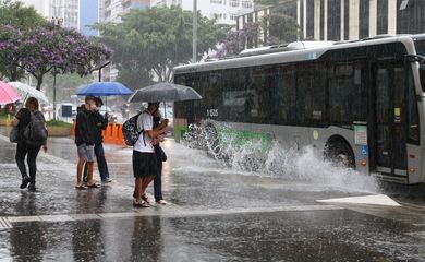 Ônibus joga água na calçada durante chuva na Avenida Paulista.