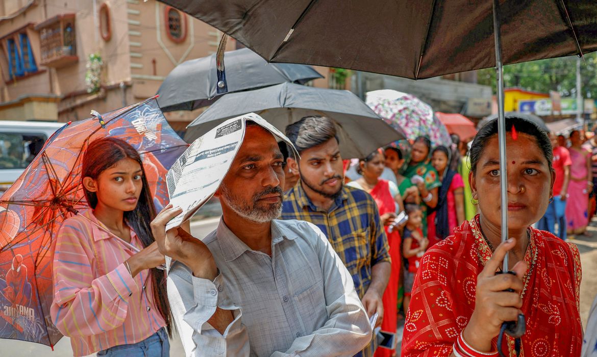 A man uses a newspaper as others use umbrellas to protect themselves from the heat as they wait to vote outside a polling station during the fifth phase of India’s general election in Howrah district of the eastern state of West Bengal, India, May 20, 2024. REUTERS/Sahiba Chawdhary